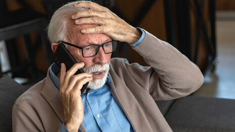 Senior telefoniert und schaut besorgt