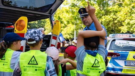 Ein Polizist vor einem Streifenwagen mit Schulkindern bei der Verkehrssicherheitsaktion »Die Schule hat begonnen« 2025 in Borna.