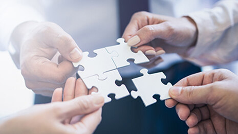 Eine Gruppe von Geschäftsleuten setzt ein Puzzle zusammen.