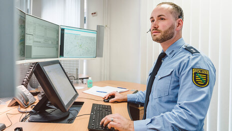 Ein Polizist am Arbeitsplatz im sogenannten »Führungs- und Lagezentrum« in der Polizeidirektion Dresden. Hier gehen zum Beispiel Notrufe ein. Bei der Polizei können Bürgerinnen und Bürger aber auch über die Onlinewache online eine Anzeige erstatten.