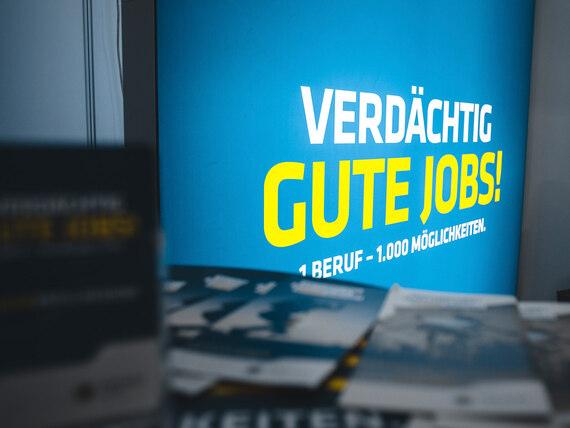 Verdächtig gute Jobs! 1 Beruf – 1.000 Möglichkeiten. Das Logo der Karrierekampagne der Polizei Sachsen auf einem Stand der Berufsberatung. Die Berufsberaterinnen und Berufsberater informieren vor Ort über die Polizeikarriere.