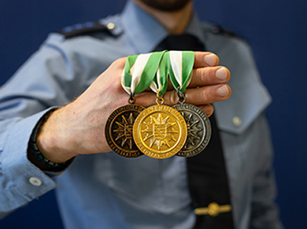 Foto: Beamter hält Medaillen in der Hand