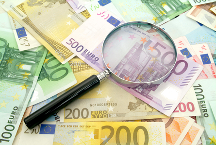 Lupe auf verschieden Geldscheinen in Euro