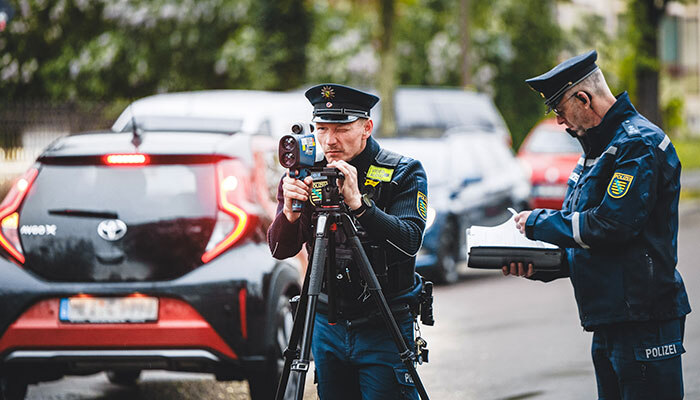 Ein Polizist steht am Straßenrand mit einem Lasergerät
